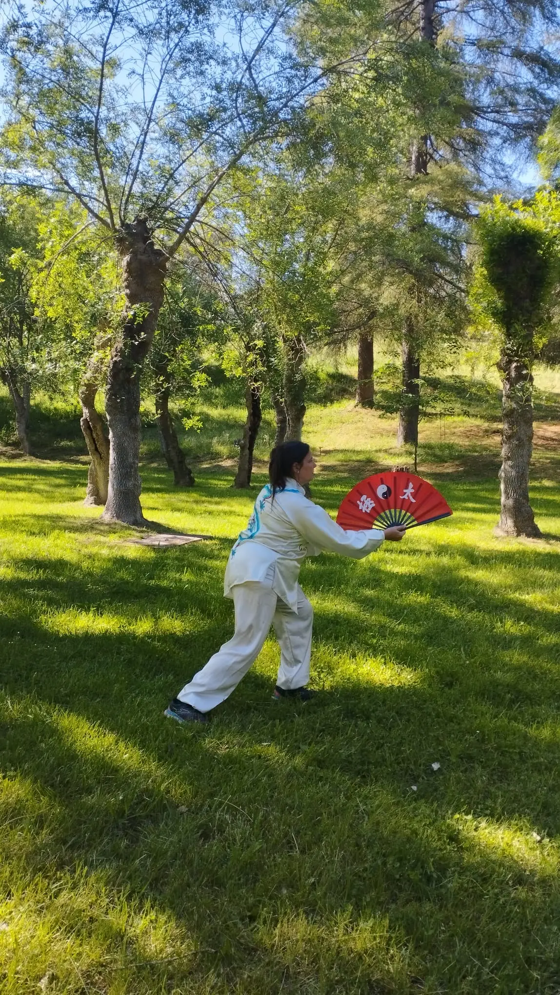 Maite García con abanico rojo de Tai Chi en parque
